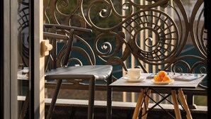 A balcony with a table, a chair, and a view of flags. - Bogishamol Hotel (Samarkand)