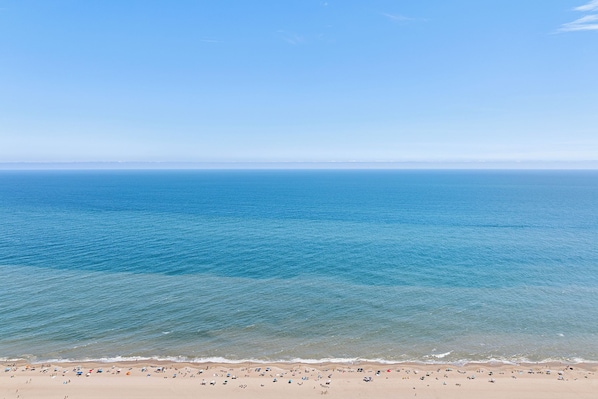 Une plage avec une eau d’un bleu limpide et un rivage sablonneux.
