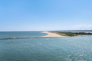 A coastal landscape with a sandy beach, calm sea, and a clear sky.