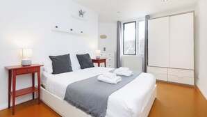 Une chambre d’hôtel avec un lit, des tables de chevet, une armoire et une fenêtre donnant sur un paysage agréable.