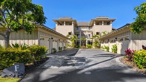 A residential building with a central entrance, multiple garages, and a landscaped driveway. - Newly Renovated Top Floor Luxury Waikoloa Beach Villa F32, Fairway Views!! (Waikoloa)