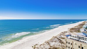 A coastal hotel with a beach view, a sandy shoreline, and a clear blue sky. - The Oasis at Orange Beach 1102 (Orange Beach)