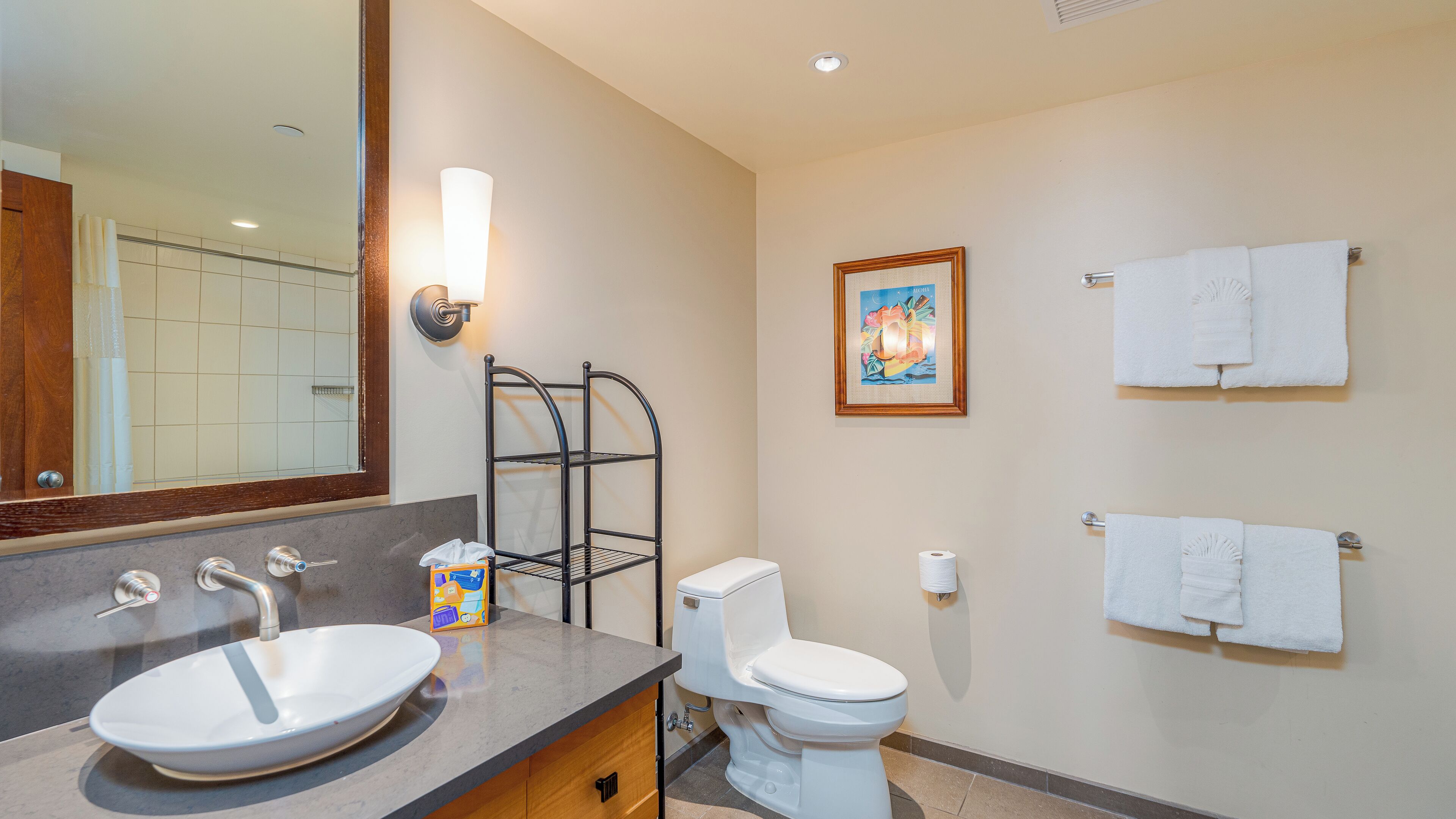 A bathroom with a sink, toilet, towel rack, and a framed picture on the wall.