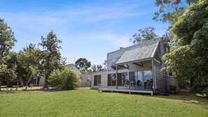 A modern house with a large deck, surrounded by a well-maintained lawn and trees. - Avon - Waterfront Retreat: Secluded lodges perfect for nature lovers (Forge Creek)