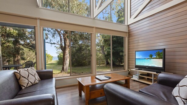 A modern living room with a large TV, comfortable seating, and a view of the outdoors.