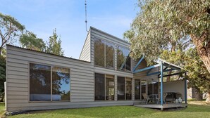 A modern two-story house with large windows, a covered patio, and a satellite dish.