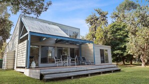 A single-story house with a covered porch, large windows, and a small deck area. - Dargo - Waterfront Retreat: Secluded lodges perfect for nature lovers (Forge Creek)