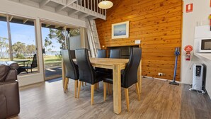Un comedor moderno con mesa y sillas de madera, vistas al exterior y un techo con vigas a la vista.