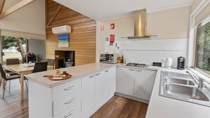 Une cuisine moderne avec des armoires blanches, un plafond en bois et une grande fenêtre.
