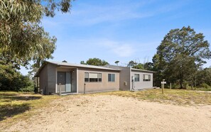 A single-story building with a flat roof, a front door, and a small porch area.