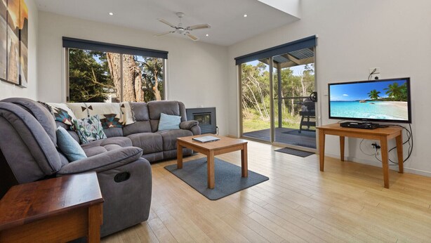 A modern living room with a grey sofa, a wooden coffee table, and a television on a stand. - Secluded lodges perfect for nature lovers (Forge Creek)