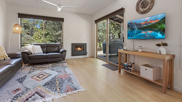 Een moderne woonkamer met een open haard, een bank, een televisie en een houten salontafel.