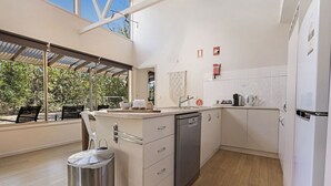 Een moderne keuken met een vaatwasser, een spoelbak en een koffieapparaat. Er is een raam met uitzicht op het buitenland.