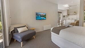 Een moderne slaapkamer met een bed, een bank, een kleine tafel en een televisie aan de muur.