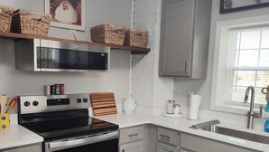 A modern kitchen with stainless steel appliances, grey cabinets, and a wooden floor.