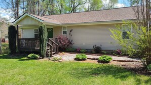 A single-story house with a front porch, a green door, and a small garden with various plants and flowers.
