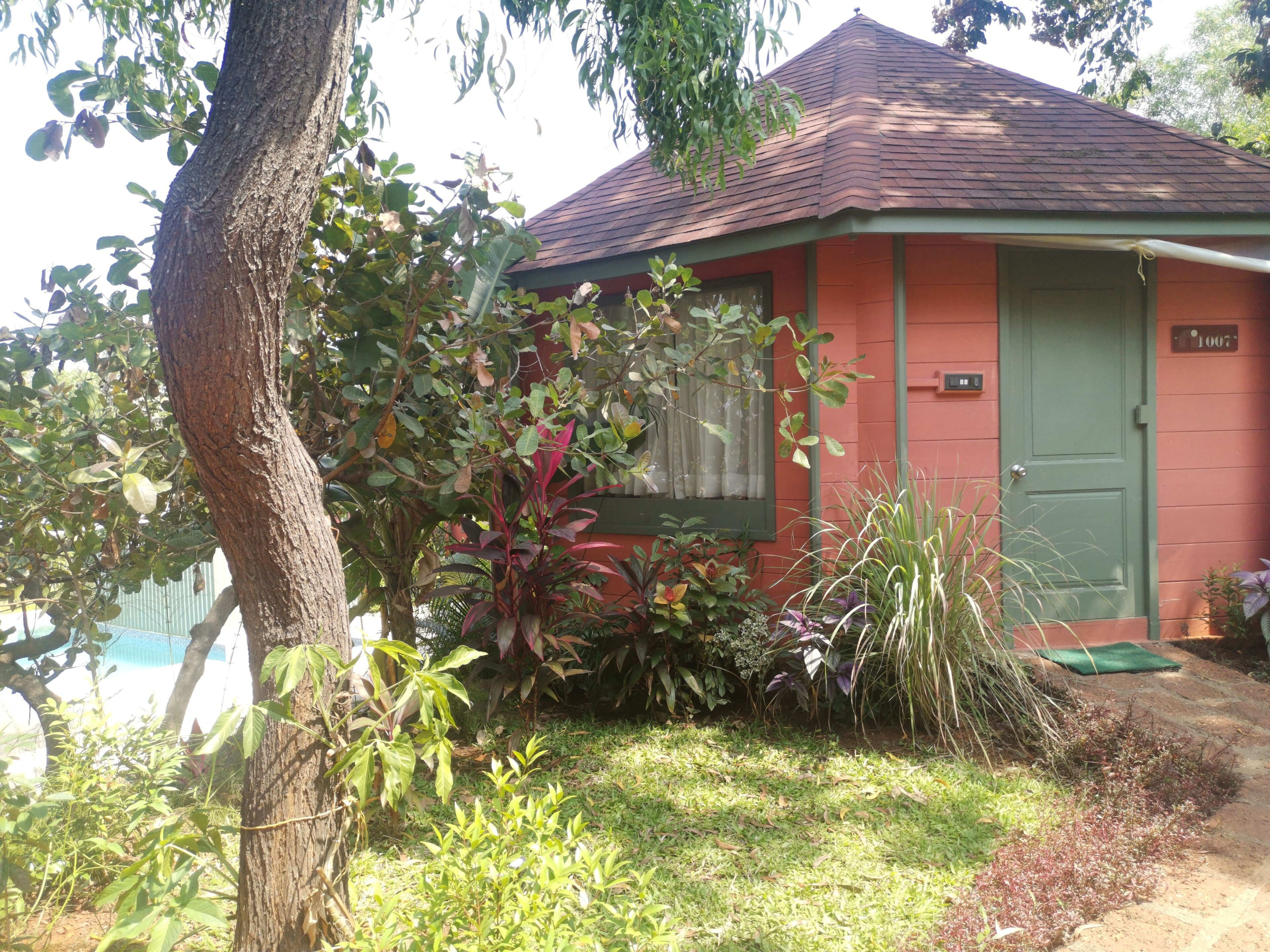 A small, single-story building with a red exterior and a green door.