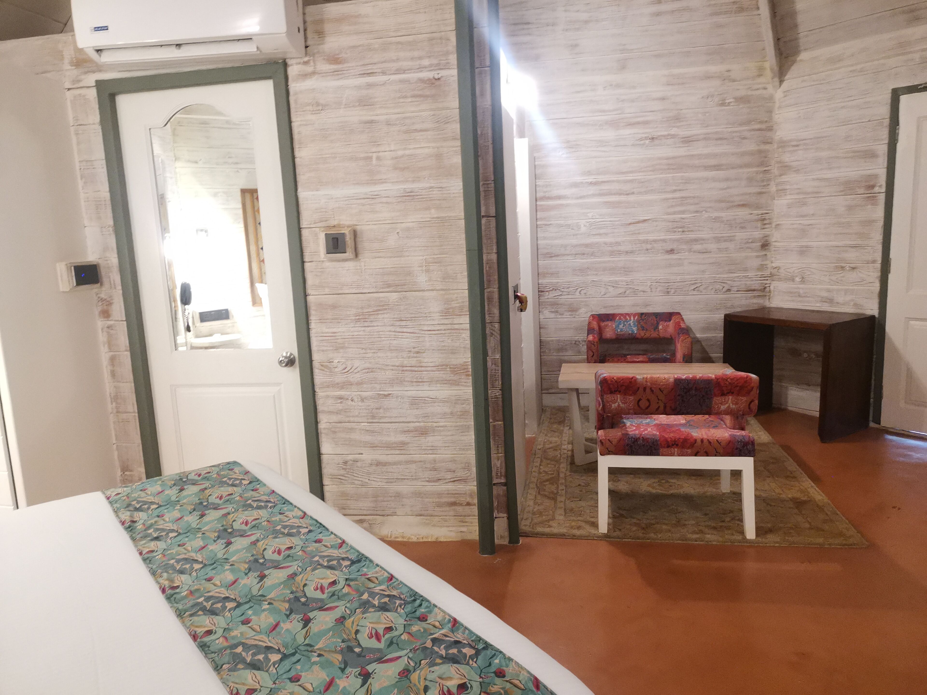 Una habitación con una cama, un sofá estampado, una mesita y una pared de madera.