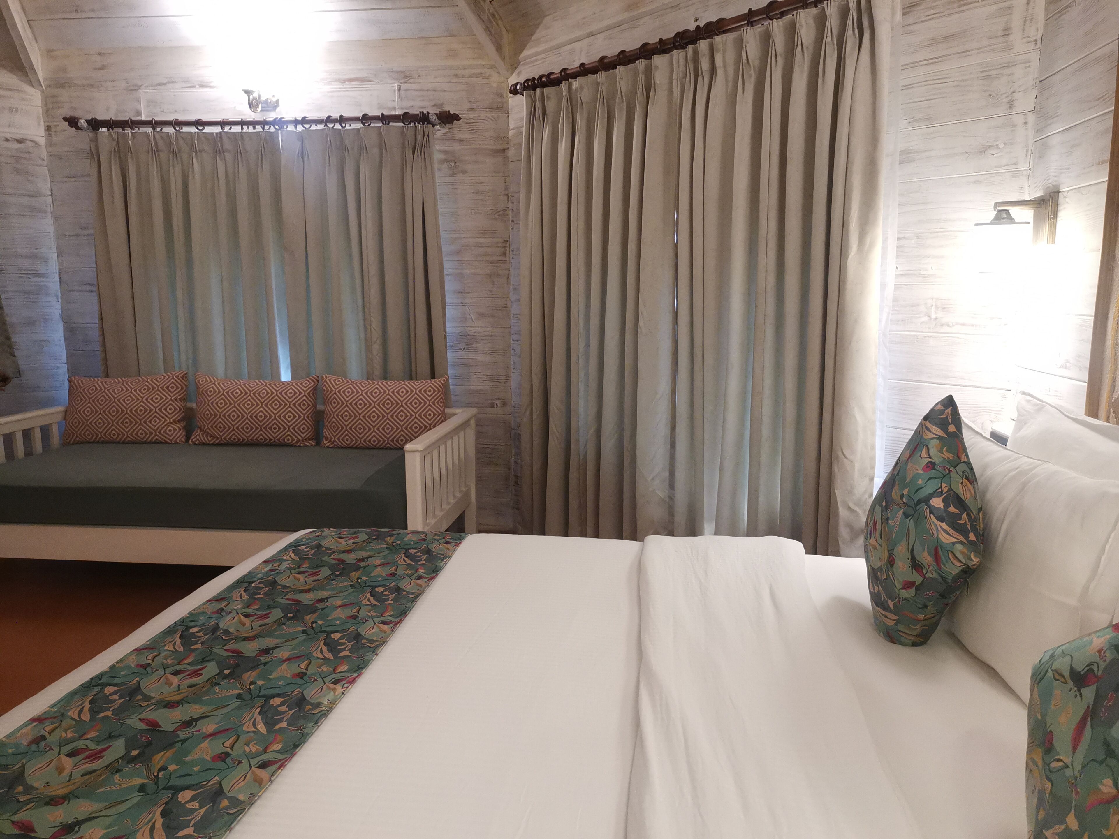 A room with a bed, a bench, and curtains.
