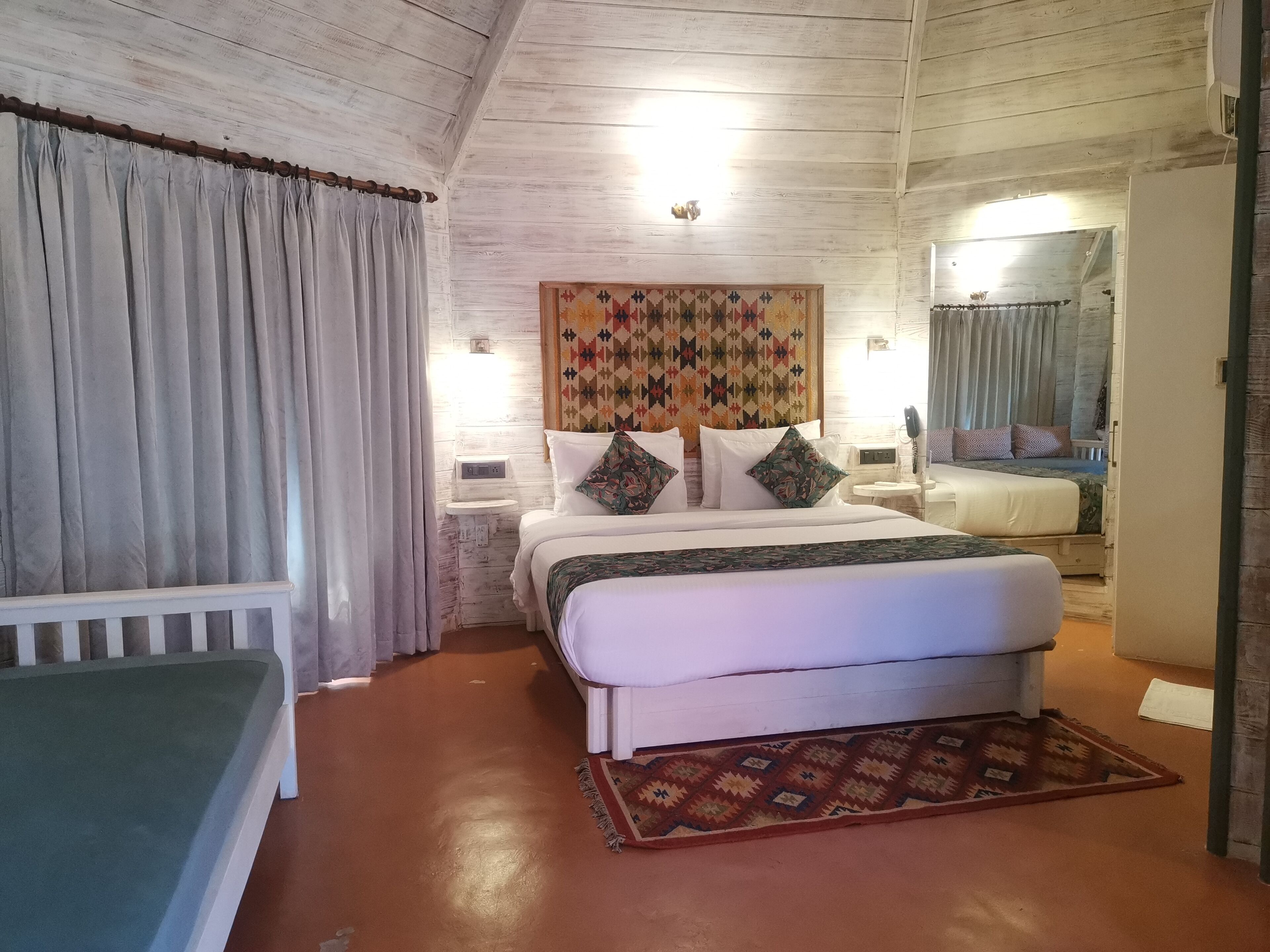 Une chambre à coucher comprenant un lit, des tables de chevet, une commode, une chaise et un tapis à motifs.