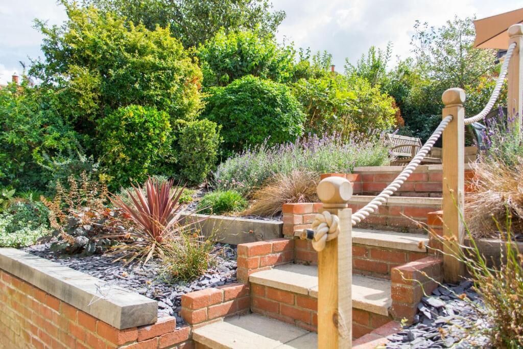A garden with a brick staircase leading to a wooden deck.