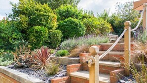 A garden with a brick staircase leading to a wooden deck. - Host & Stay | Laylands Yard (Wells-next-the-Sea)