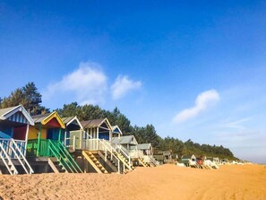 Une rangée de cabanes de plage, chacune accessible par quelques marches, se dressant sur fond de ciel bleu azur.