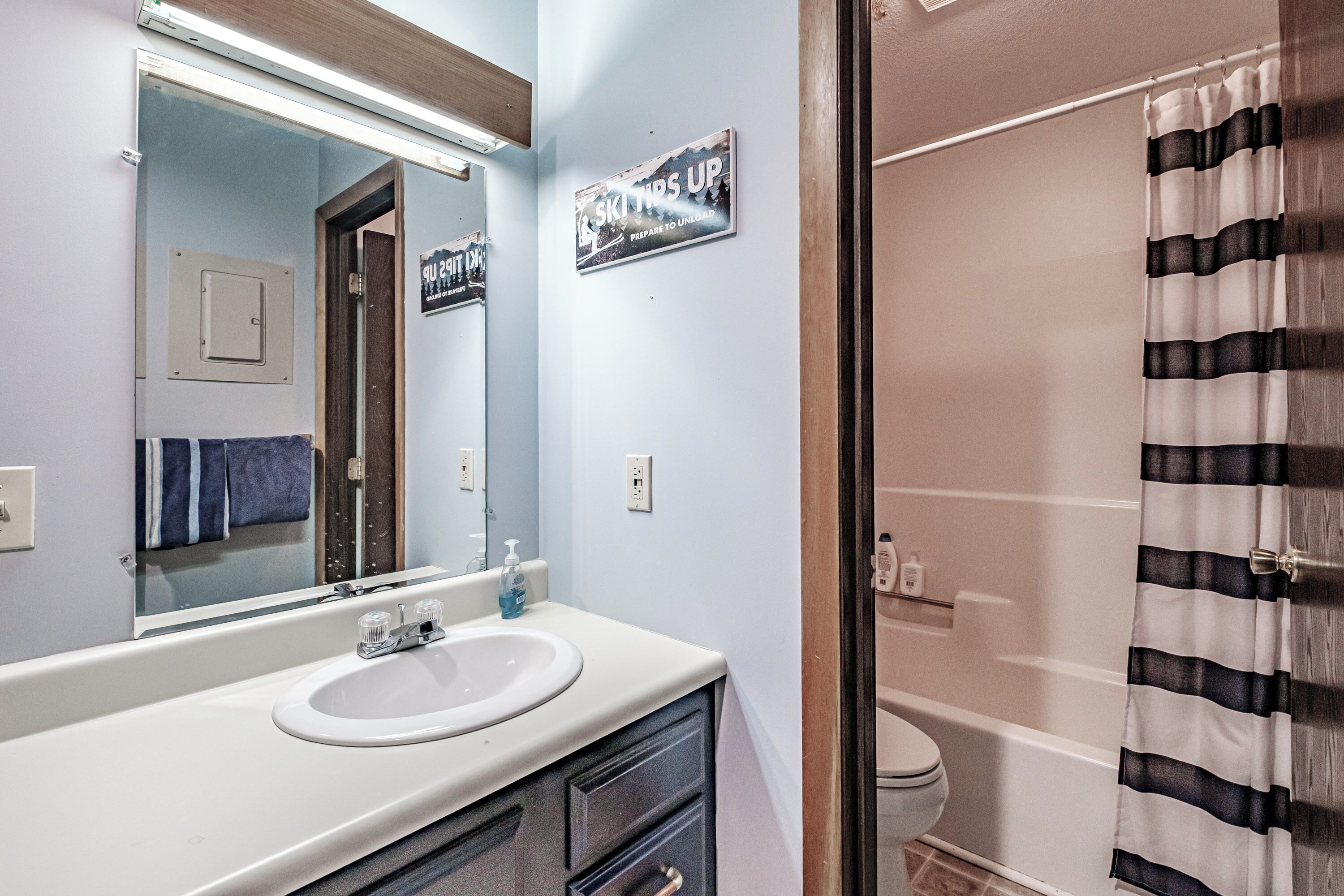 A bathroom with a sink, mirror, and a sign that reads "SKY HIGH PREPARE TO UNLOAD".