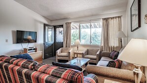 A cozy living room with a sofa, armchairs, a coffee table, and a TV. - Cascades Ski-in/Ski-out one bedroom sleeps 7 (Newry)