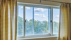 A window with two curtains, a view of trees, and a clear sky. - Cascades Ski-in/Ski-out one bedroom sleeps 7 (Newry)