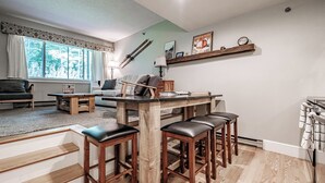 A modern kitchen with a wooden island, bar stools, and a dining table.