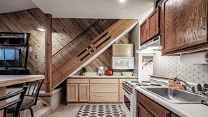 Une cuisine avec des meubles de rangement en bois, un four à micro-ondes, une cuisinière et un évier.