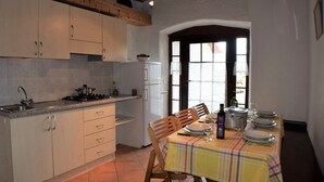 Una cocina con armarios de madera, una estufa y un comedor con mesa puesta para cuatro.