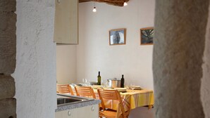 Un comedor rústico con vigas de madera a la vista, piso de baldosas y una mesa lista para comer.