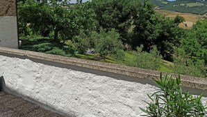 Un edificio de piedra con vistas a un paisaje rural, que incluye árboles y colinas onduladas.
