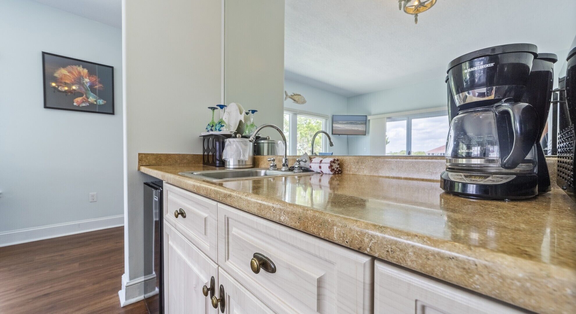 A kitchen with a granite countertop, stainless steel appliances, and a coffee maker.