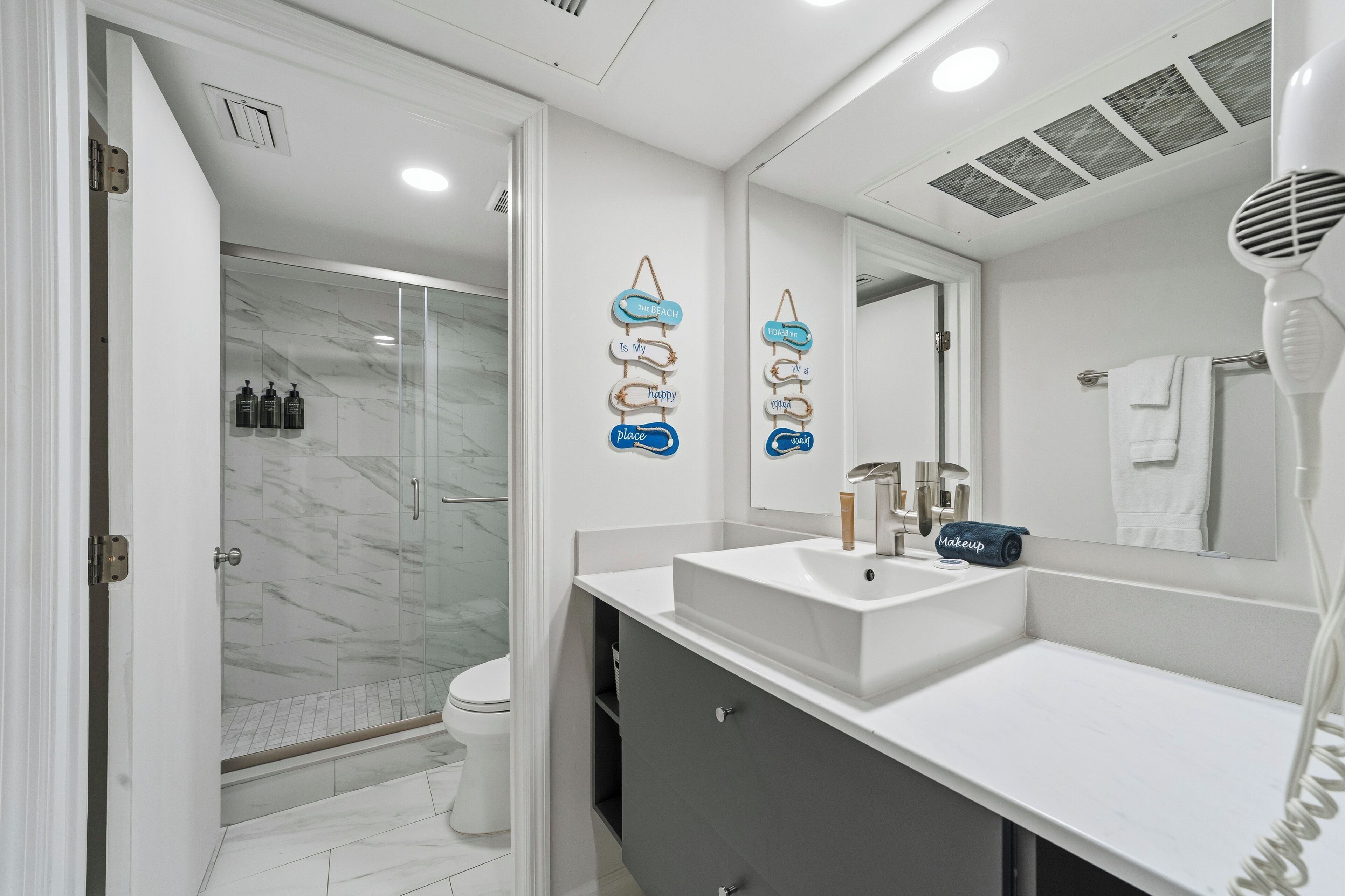 Een moderne badkamer met een glazen douchecabine, een wit wastafelmeubel en een handdoekhouder.