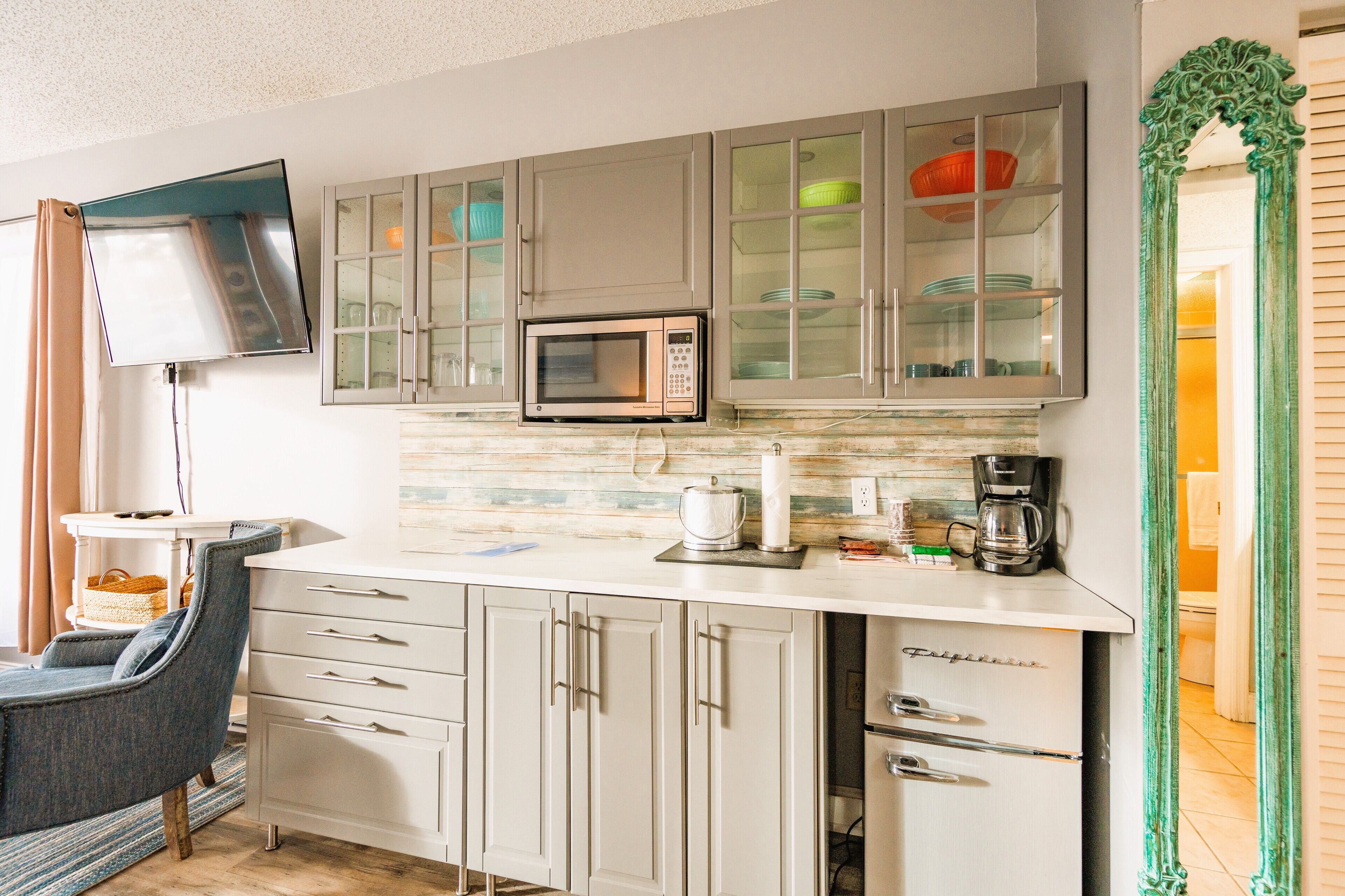 A kitchen with a microwave, coffee maker, and cabinets.