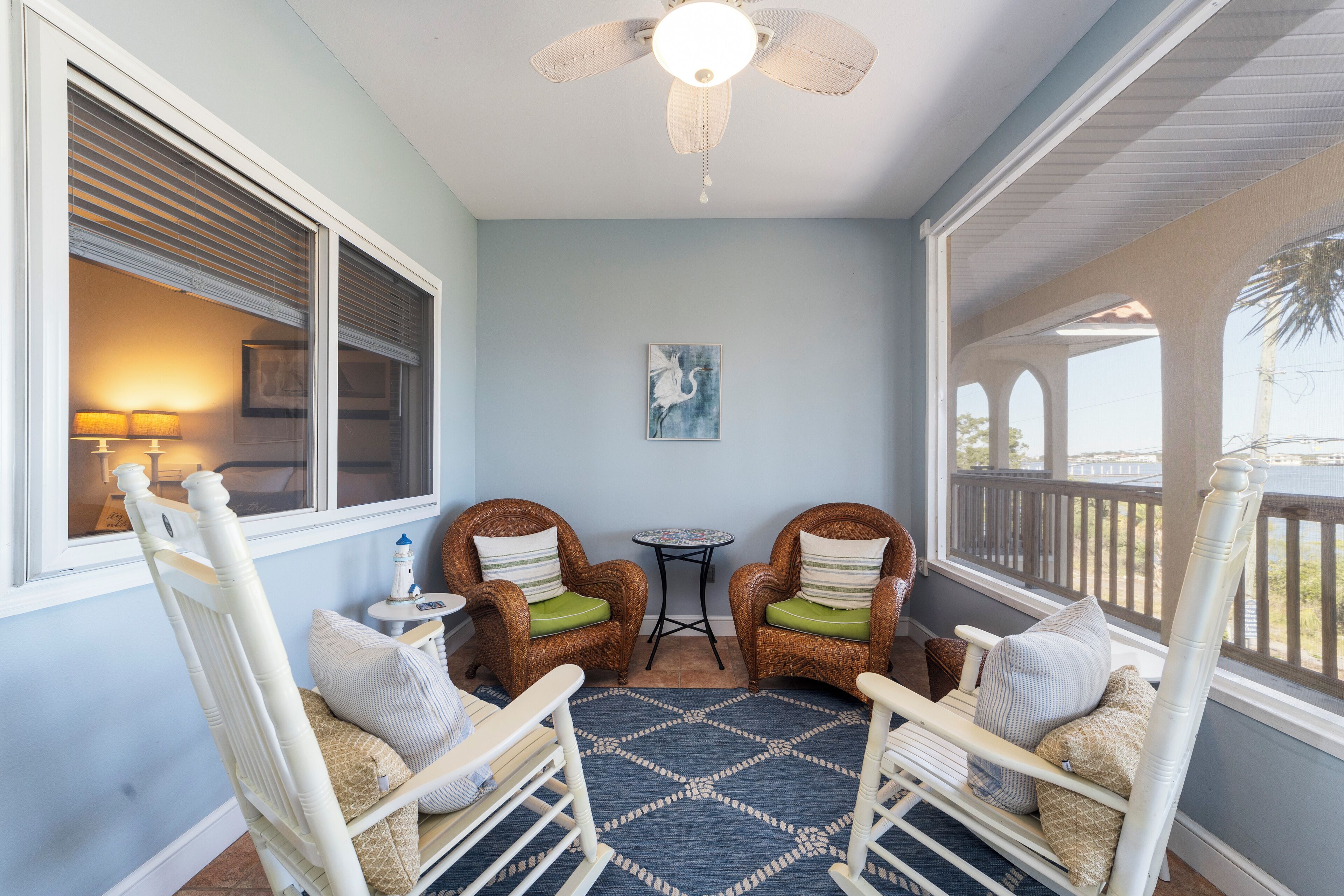 A room with two rocking chairs, a ceiling fan, a small table, and a view of the outdoors.
