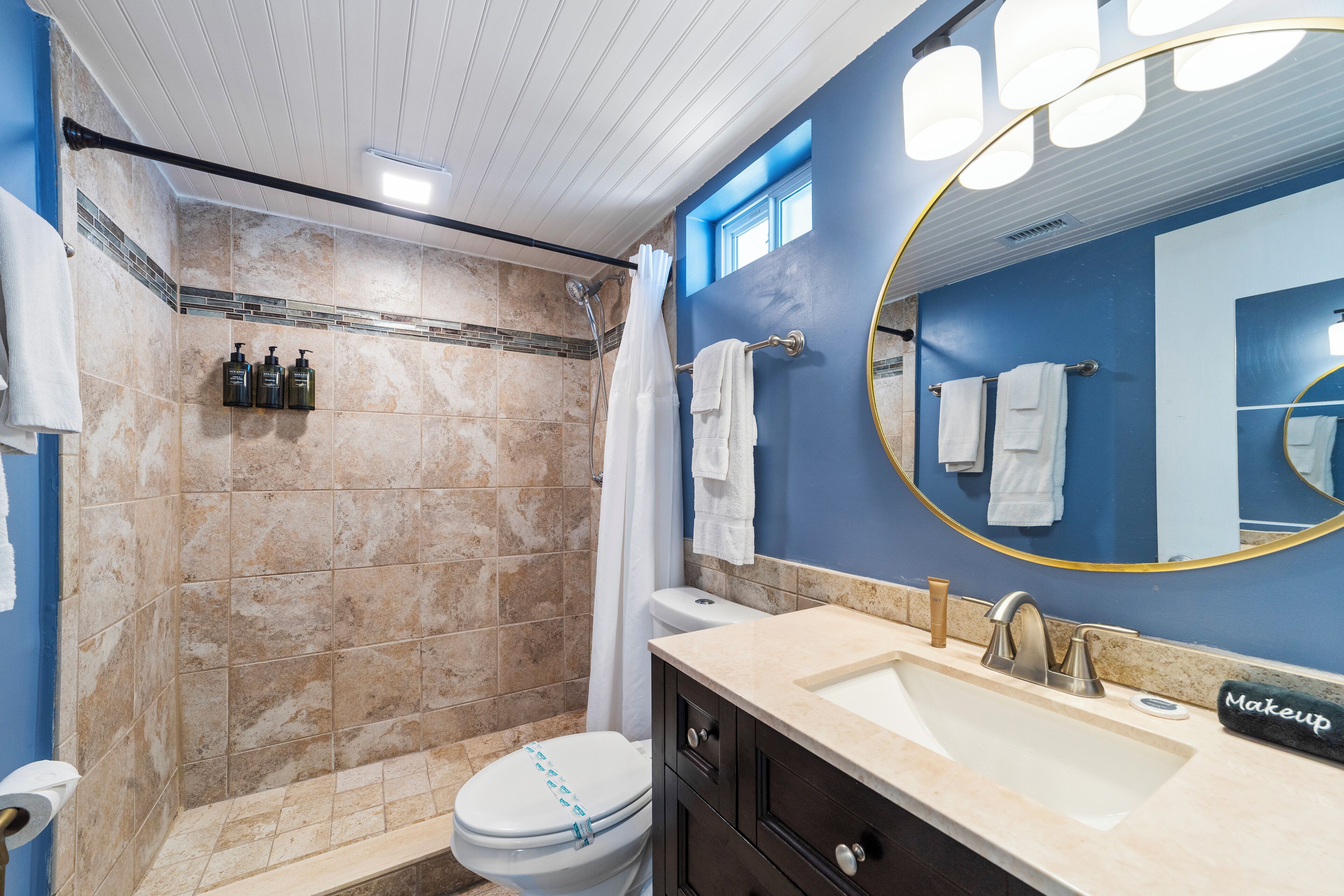 Een badkamer met douche, toilet, wastafel en een grote spiegel.