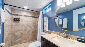 Un baño con ducha, inodoro, lavabo y un espejo grande.