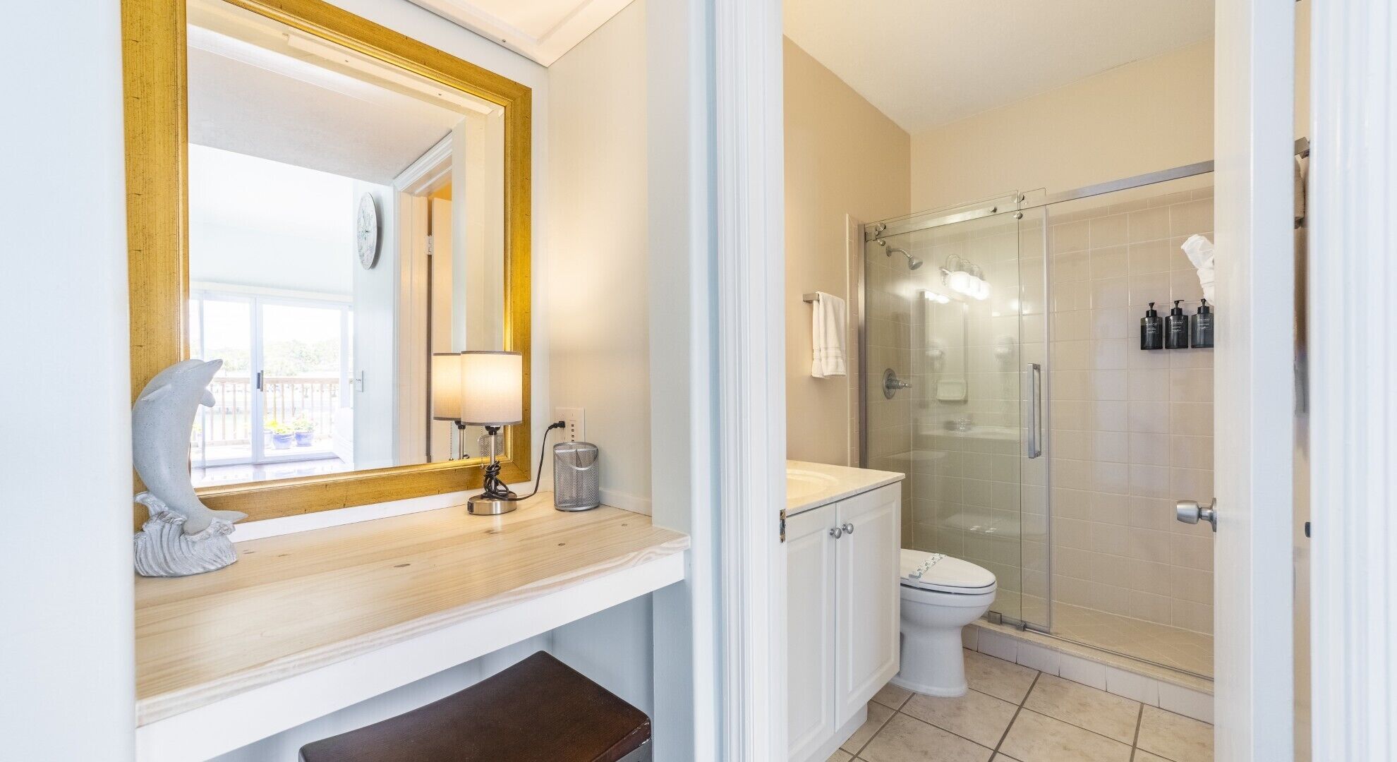 A bathroom with a wooden vanity, a mirror, a toilet, and a glass-enclosed shower.