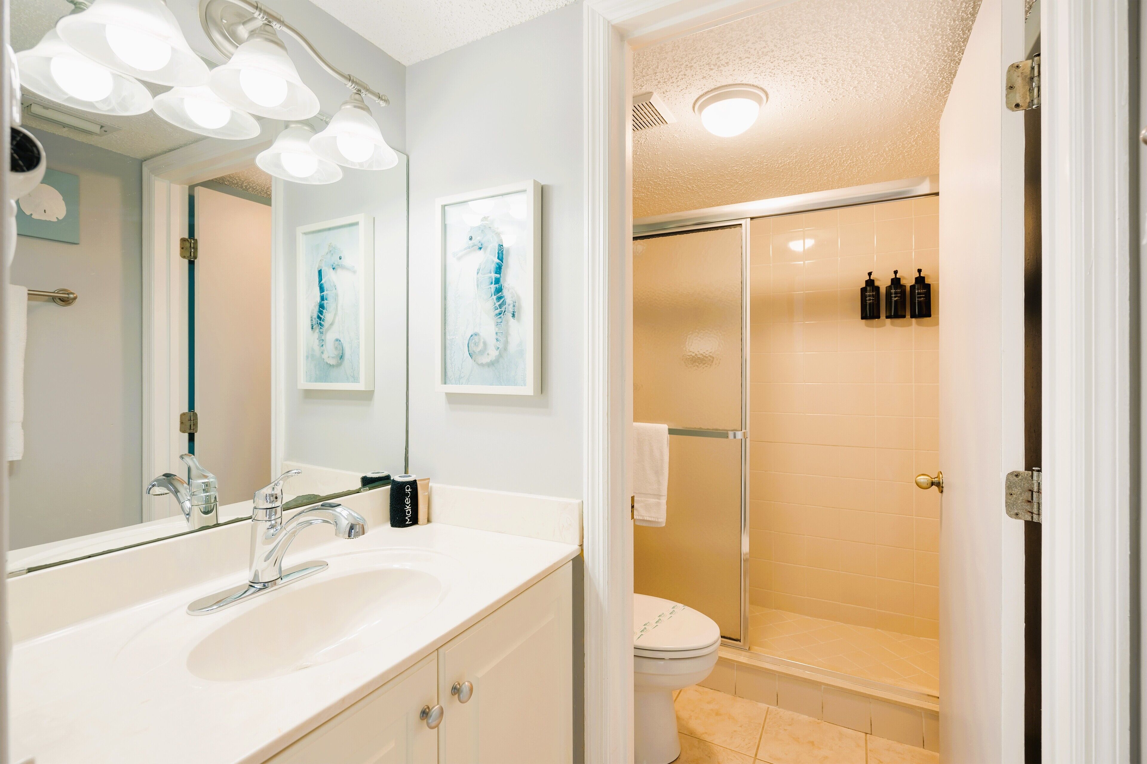 A bathroom with a large mirror, a sink, a toilet, and a shower area.