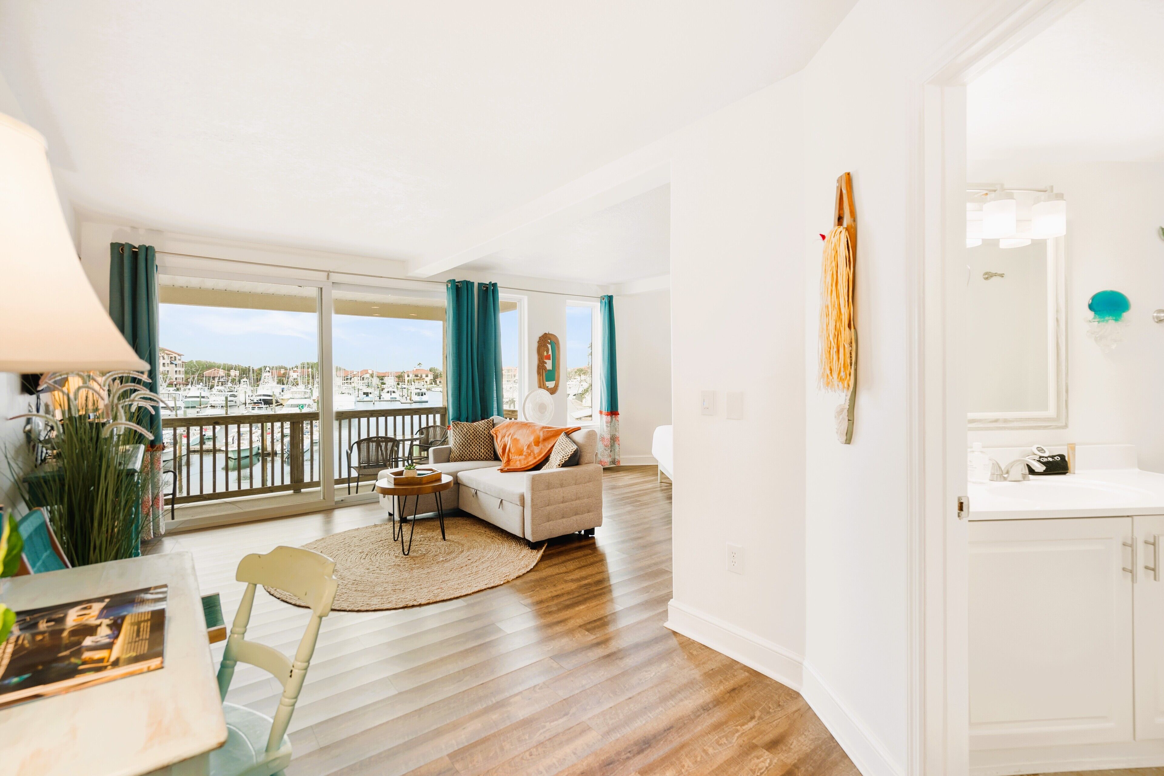 Een moderne woonkamer met balkon, een bank, een salontafel en uitzicht op een jachthaven.