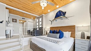 A modern bedroom with a wooden ceiling, a large bed with patterned bedding, a nightstand, and a decorative fish sculpture on the wall. - Inn at Camachee Harbor by Coolvacay (St. Augustine)
