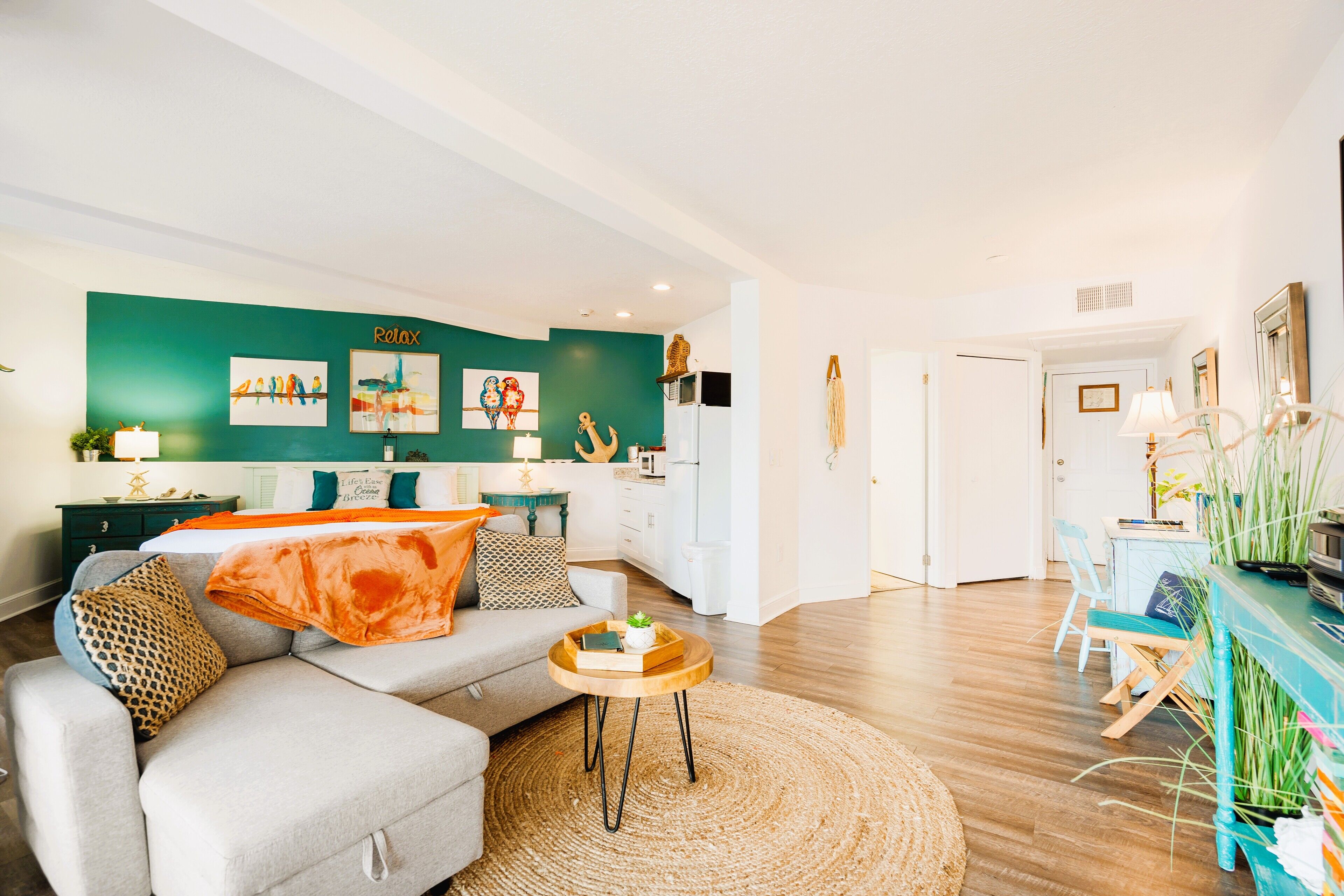 Ein modernes Wohnzimmer mit einem grauen Sofa, einem runden Couchtisch und einer grünen Akzentwand.