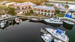 A marina with multiple boats docked, a large building with balconies, and a view of the water and sunset. - Inn at Camachee Harbor by Coolvacay (St. Augustine)