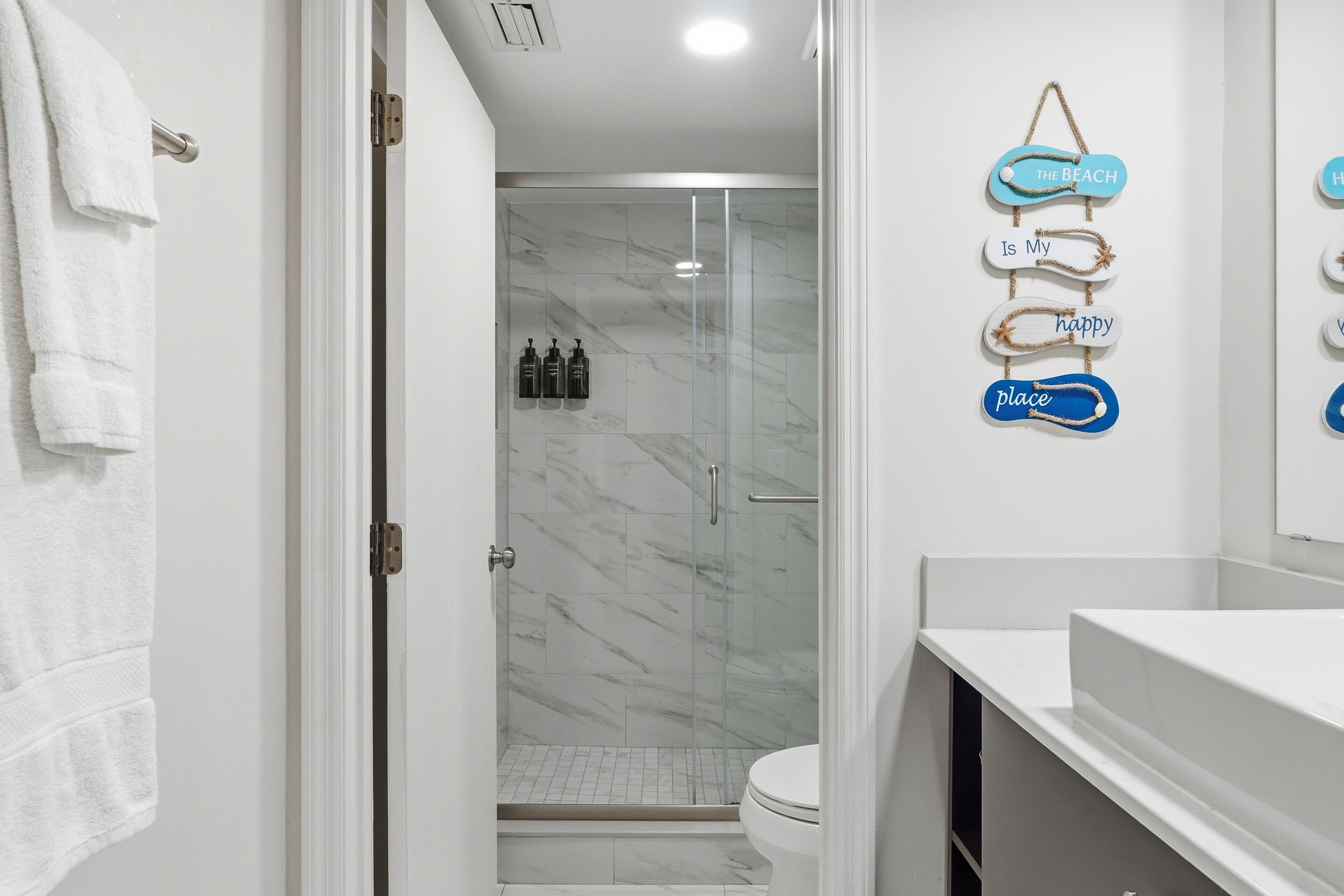 Un baño moderno con cabina de ducha de vidrio, un lavabo blanco y un perchero para toallas.
