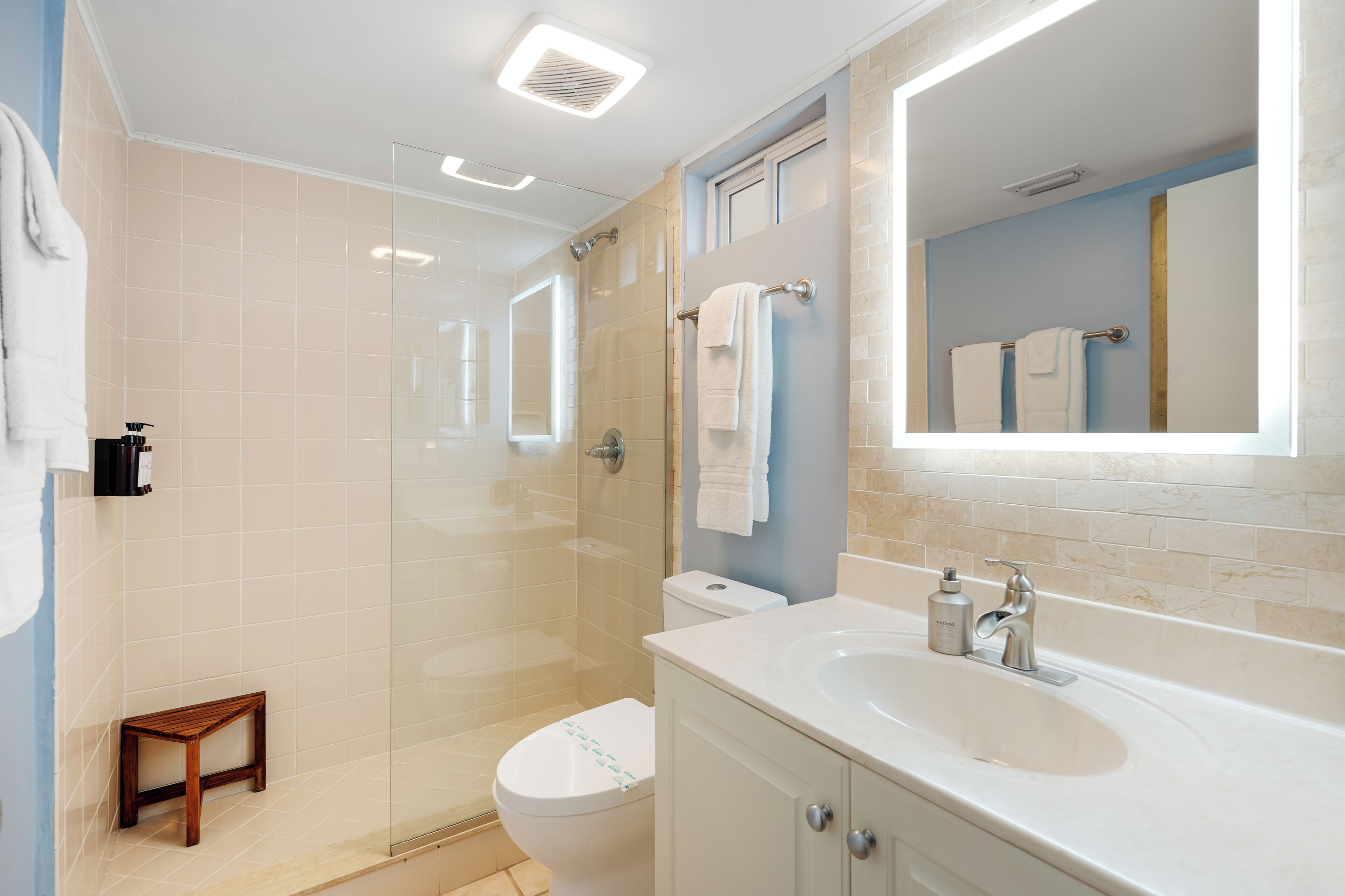 A modern bathroom with a glass-enclosed shower, a white toilet, and a large sink with a mirror above it.