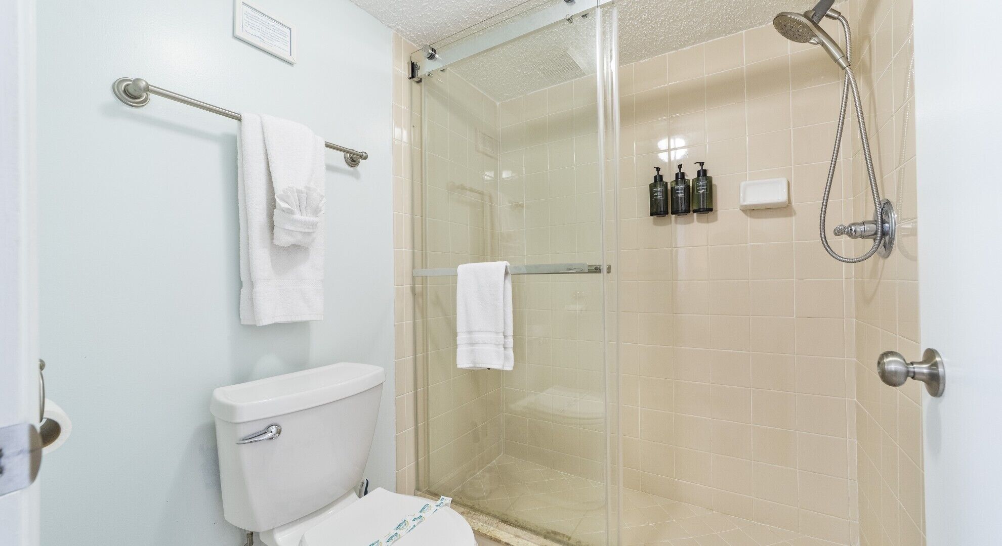 A bathroom with a toilet, a glass-enclosed shower, and a towel rack.